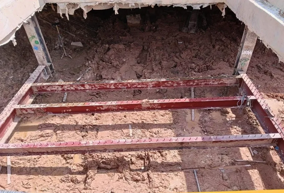 Red-painted steel members laid across an excavation on the Contract N110 site.